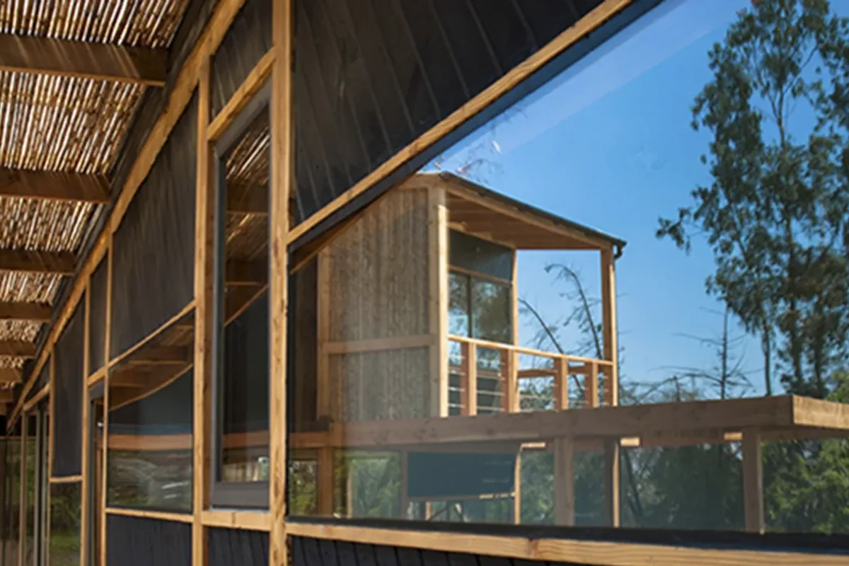 La misma casa ya construida: revestimiento de madera y ventanales terminados, obra de CCP Arquitectura